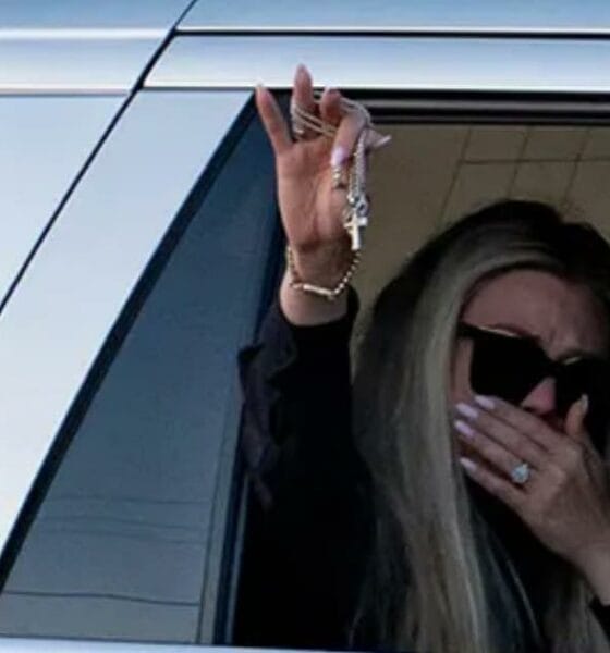 Erika Kirk waves to supporters holding Charlie Kirk’s cross necklace, a symbol of his faith and enduring legacy.